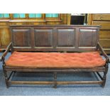 ANTIQUE OAK OPEN HALL BENCH, the back having four chamfered panels and shaped arms on turned front
