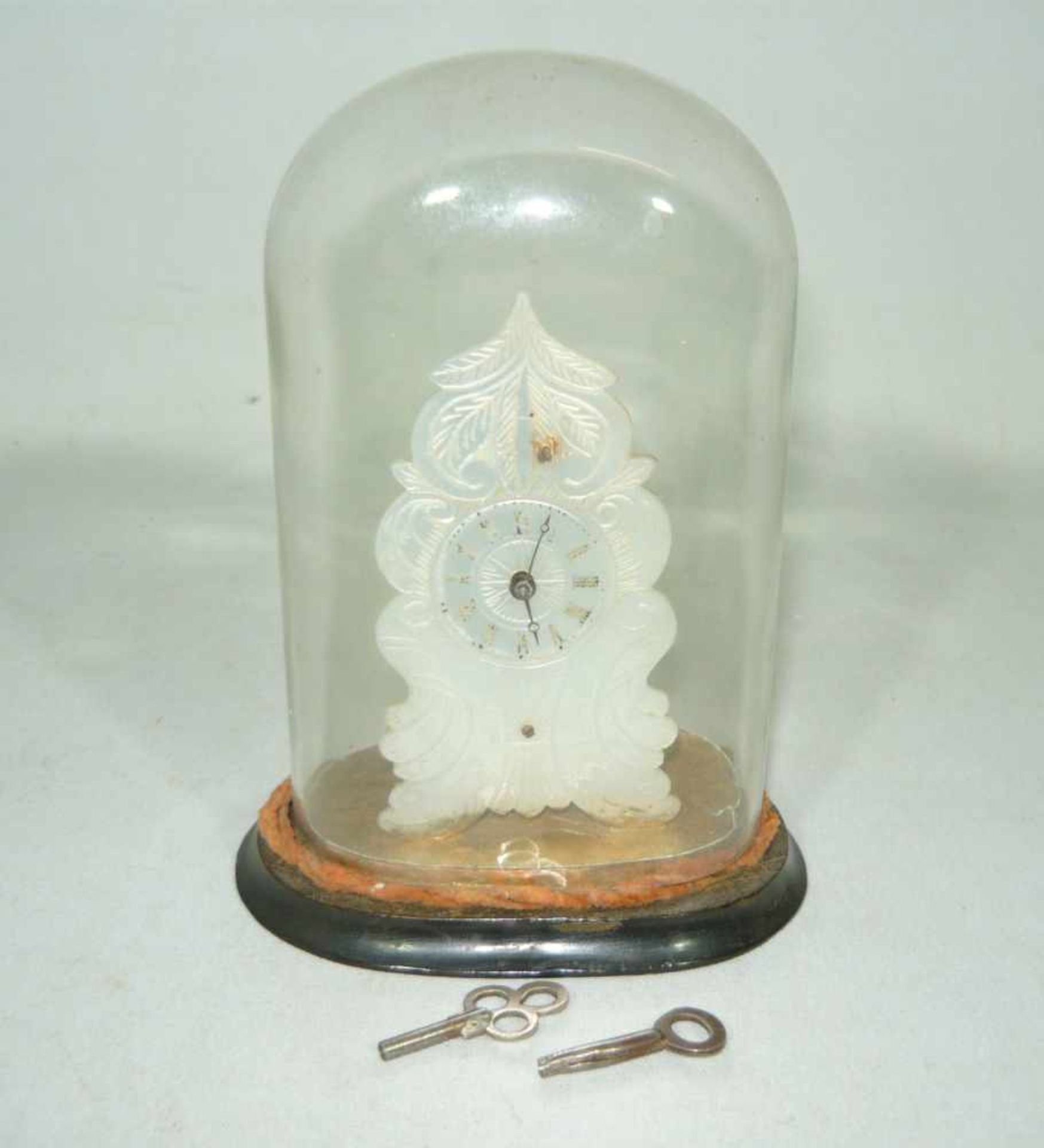 Miniaturuhr mit Perlmuttziffernblatt unter Glassturz. Wohl vor 1900. H. ca. 13 cm.Miniature watch w.
