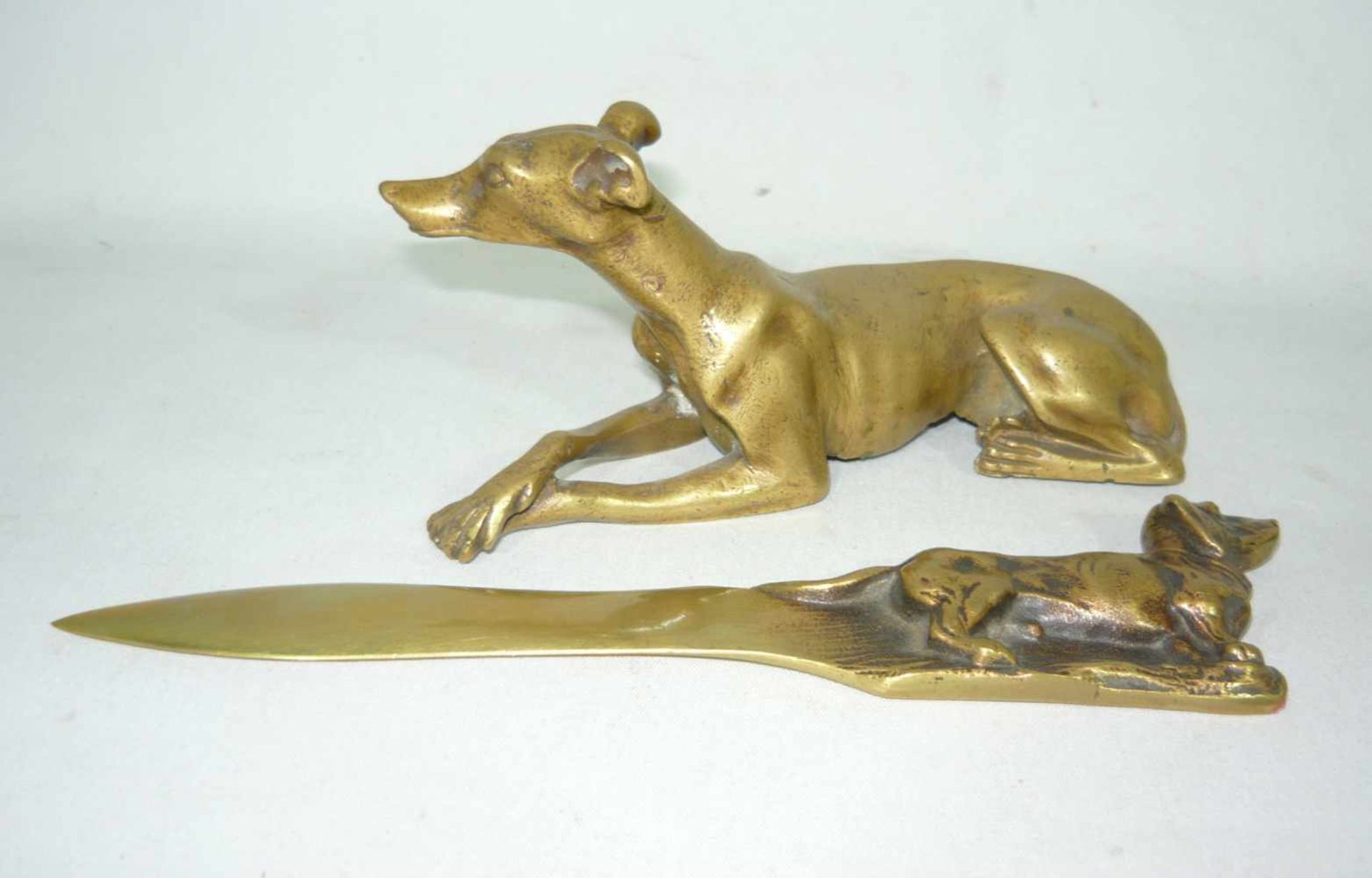 Figur eines liegenden Hundes sowie Brieföffner mit Hund. Wohl um 1900. H. ca. 15 u. 20 cm.Figure