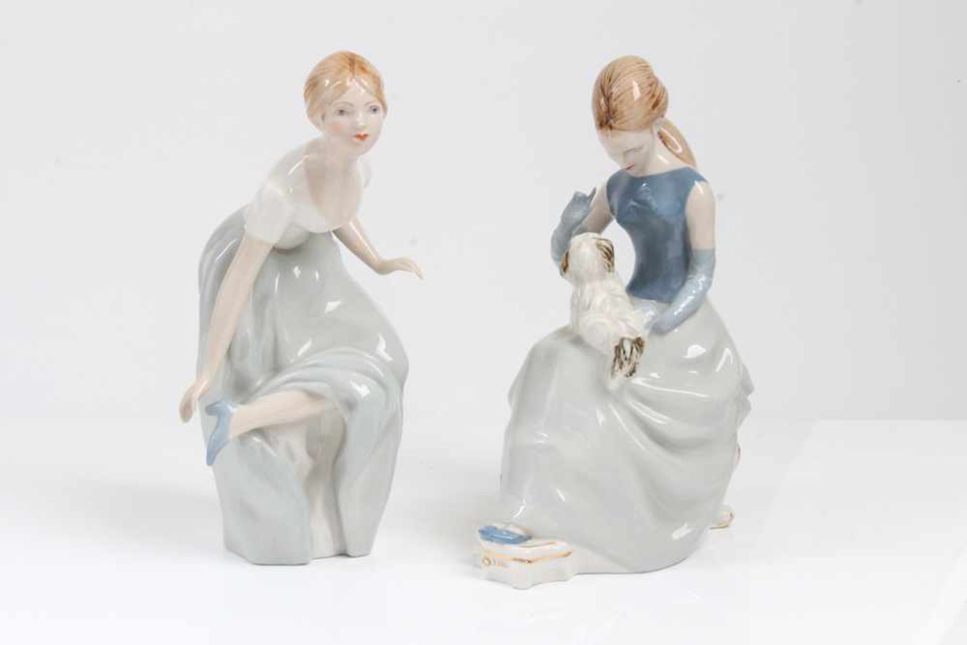 Zwei Porzellanfiguren.Royal Dux 20. Jh. Sitzende und stehende Figur in in pastelligen Kleidern.