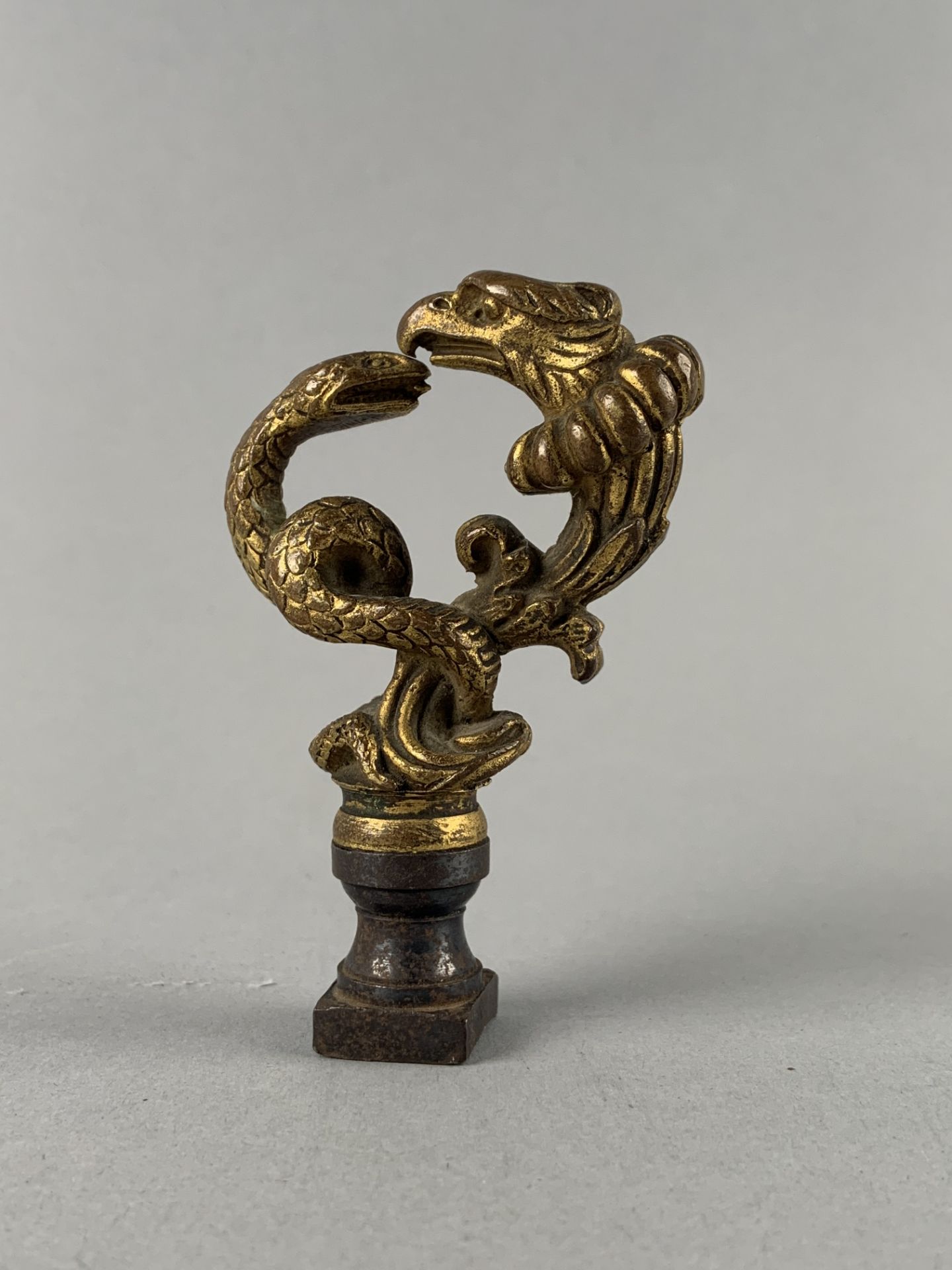 Elément en bronze à sujet d'un serpent et d'un aigle affrontés. H : 8.5 cm. -