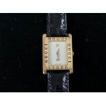 GUCCI. montre de dame carrée dorée, bracelet cuir vernis noir. -