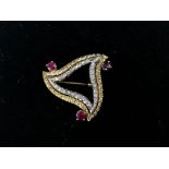 Broche de forme triangulaire en or, diamants et trois rubis. P. 10,5 g. -