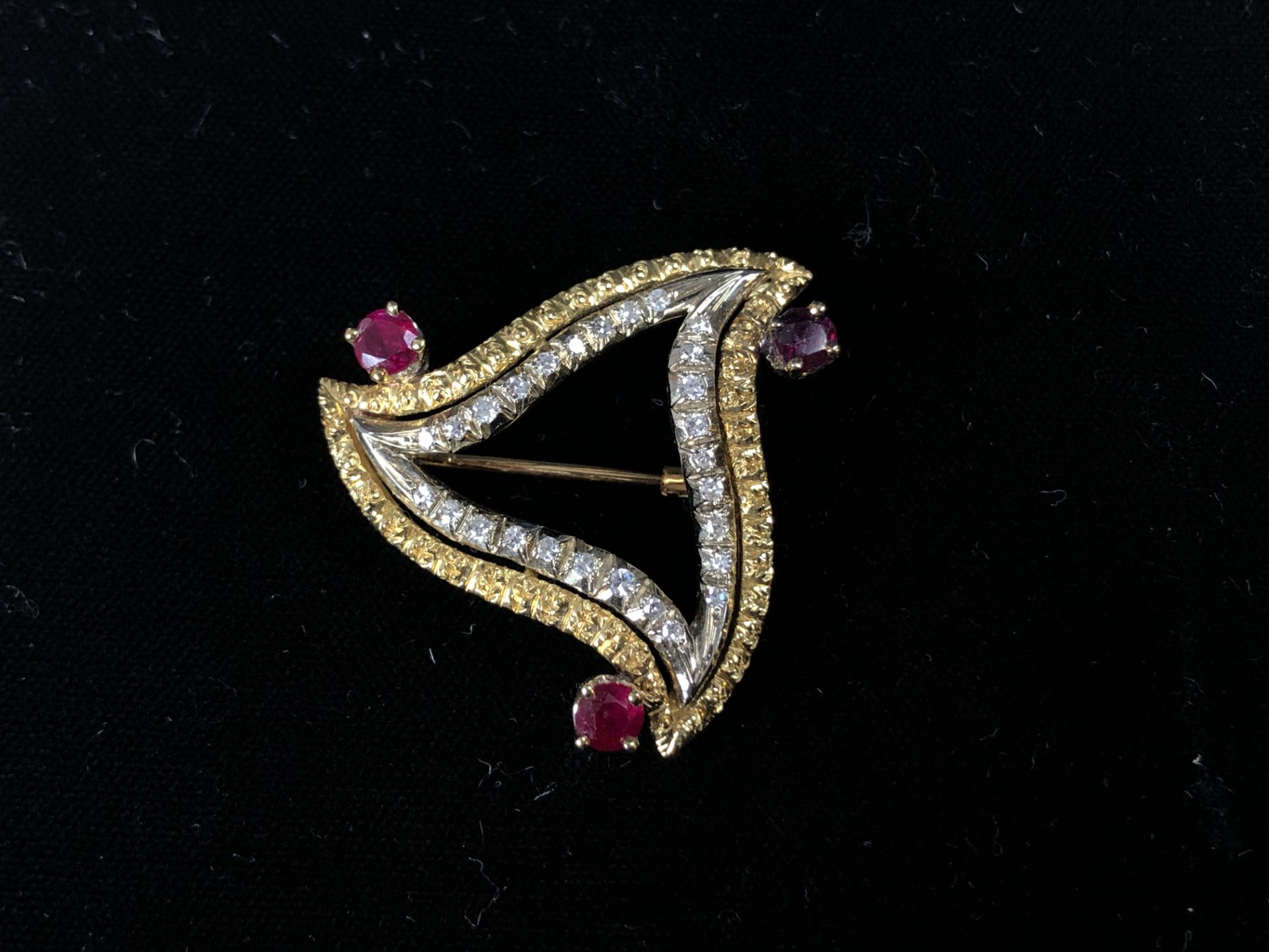 Broche de forme triangulaire en or, diamants et trois rubis. P. 10,5 g. -