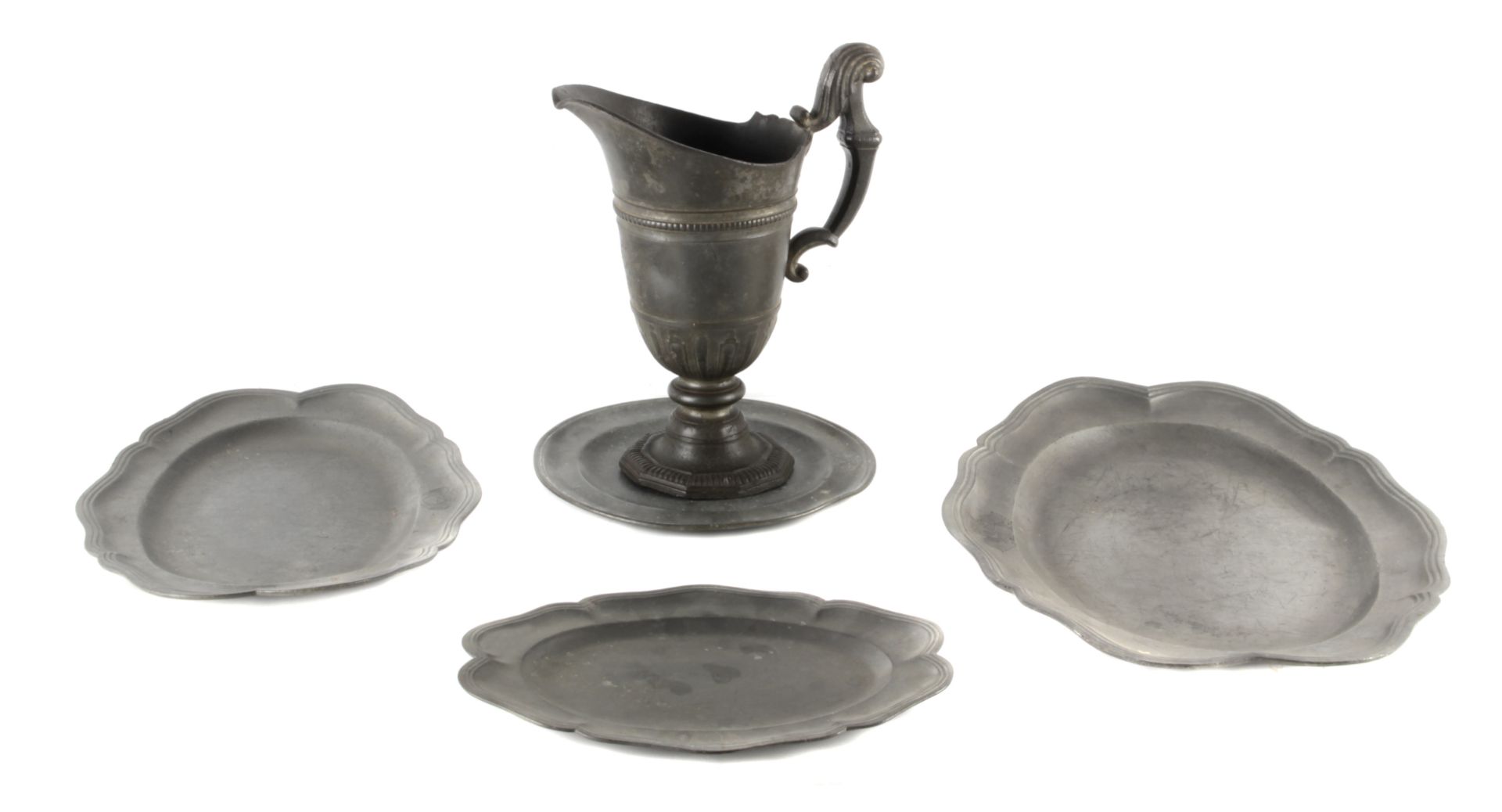 An 18th century set of three tin serving trays, a dish and a jug