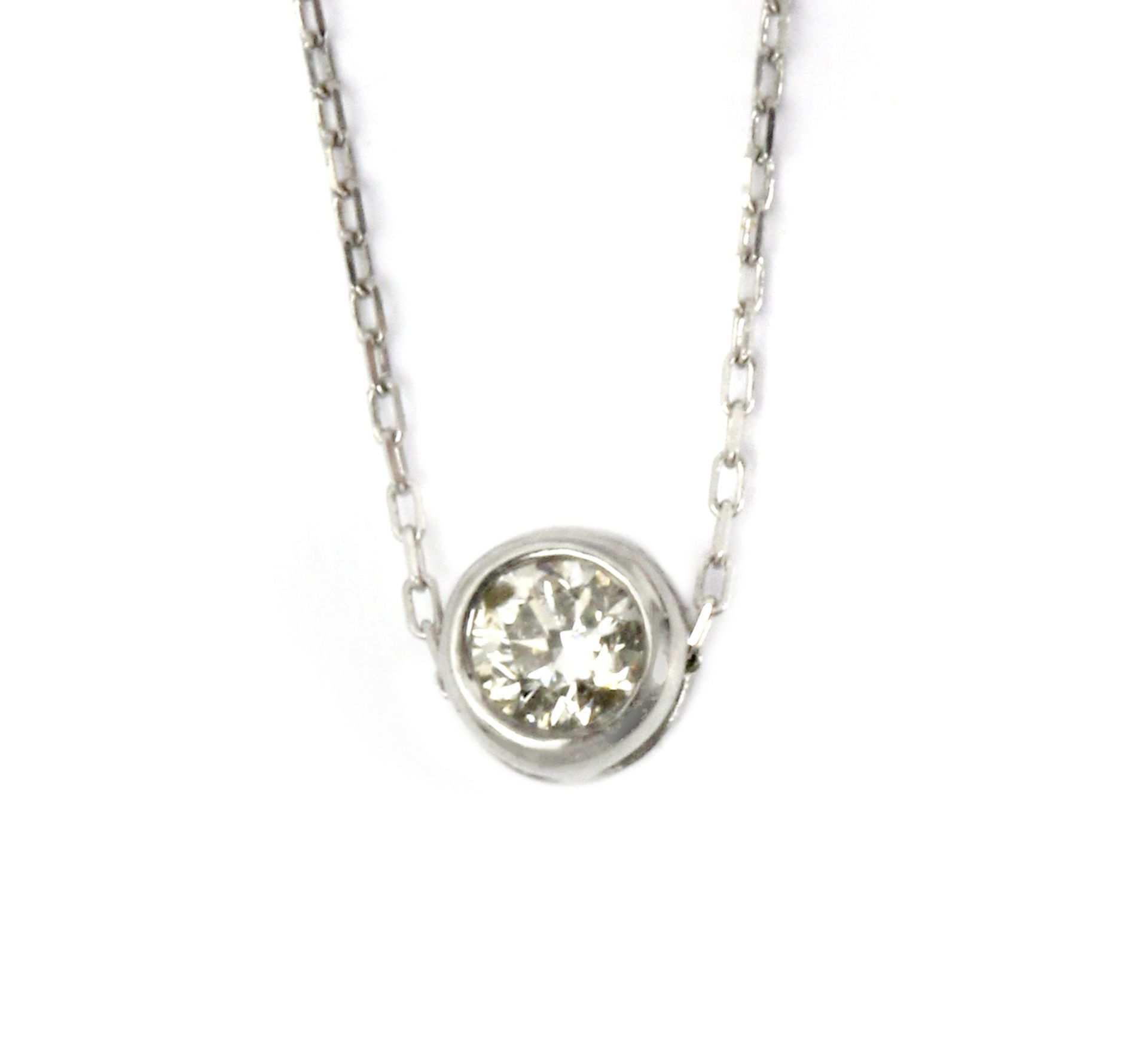 A 0,10 ct. round brilliant cut diamond bezel pendant with a platinum setting and chain