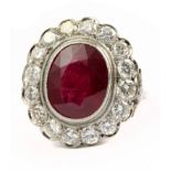 An oval cut ruby and round brilliant cut diamonds cluster ring with a platinum setting