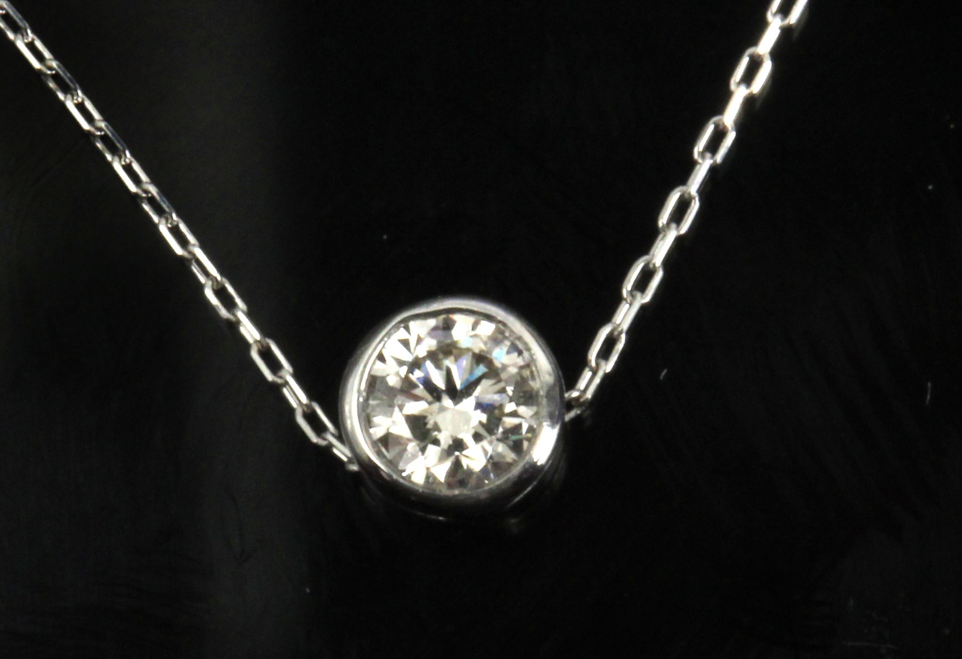 A 0,20 ct. round brilliant cut diamond bezel solitaire pendant with a plantinum setting and chain
