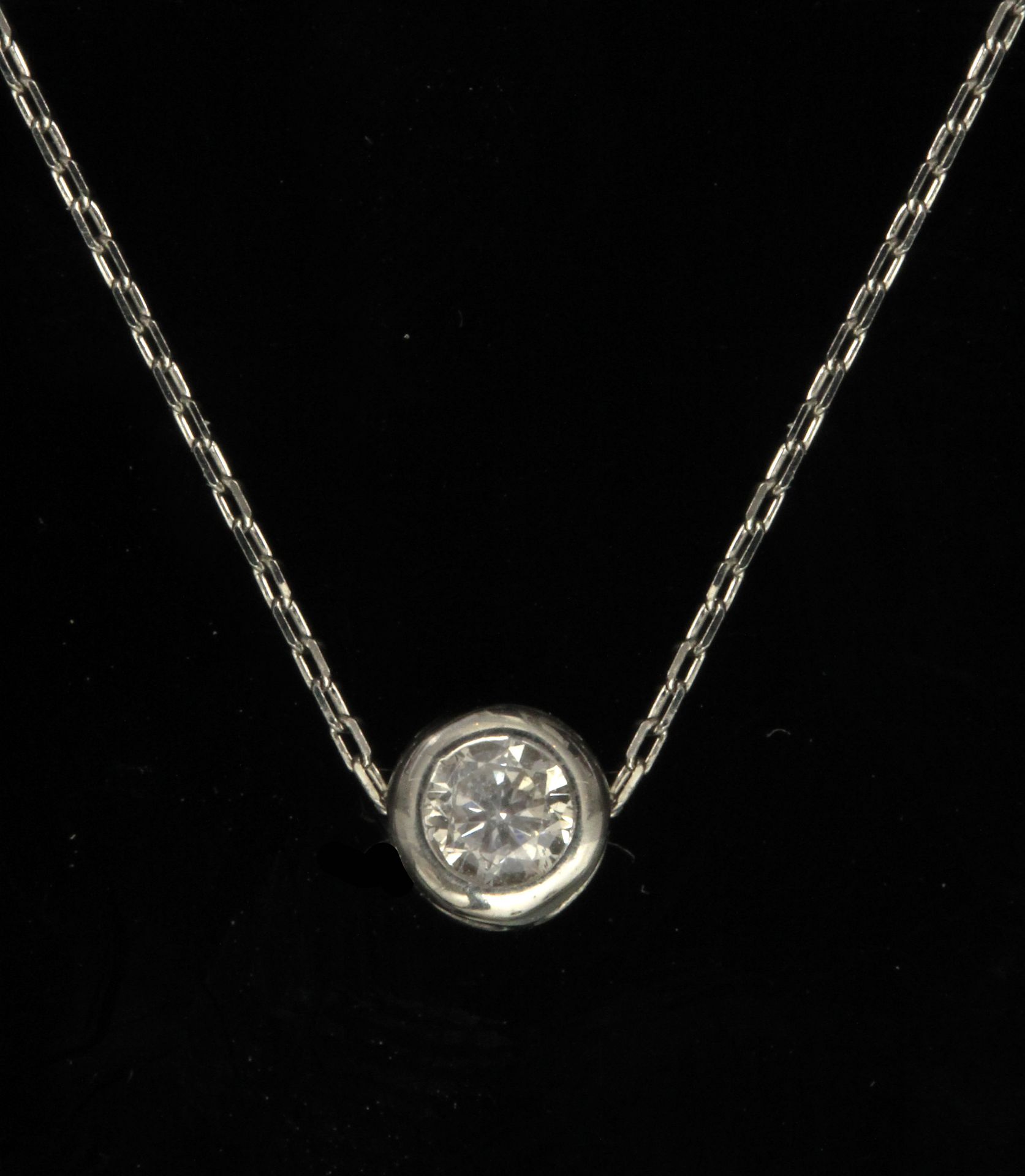 A 0,10 ct. brilliant cut diamond (H-I, SI1) platinum bezel pendant and chain