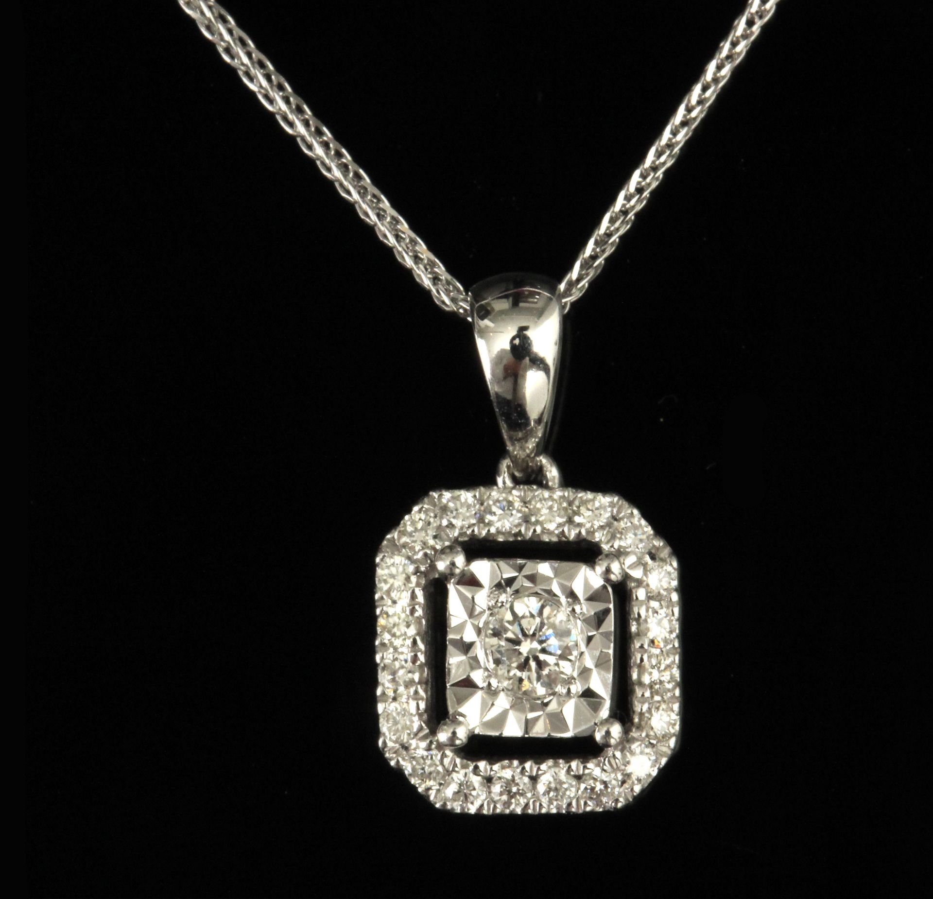 A brilliant cut diamond cluster pendant with an 18 k. white gold setting