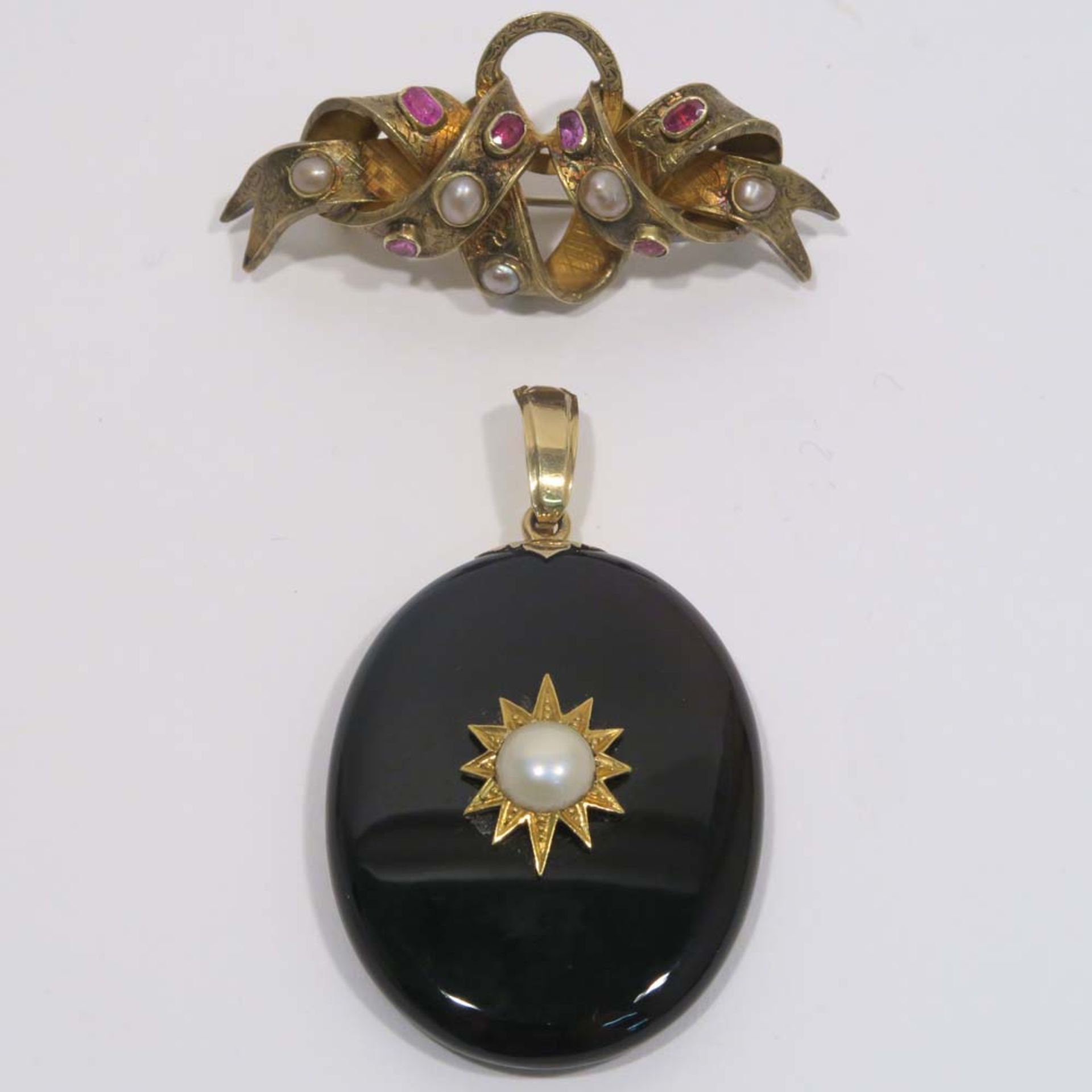 Brosche und AmulettSchleifenförmige Brosche, 14 K GG mit Perlen und Rubinen; Ovales Amulett aus Onyx