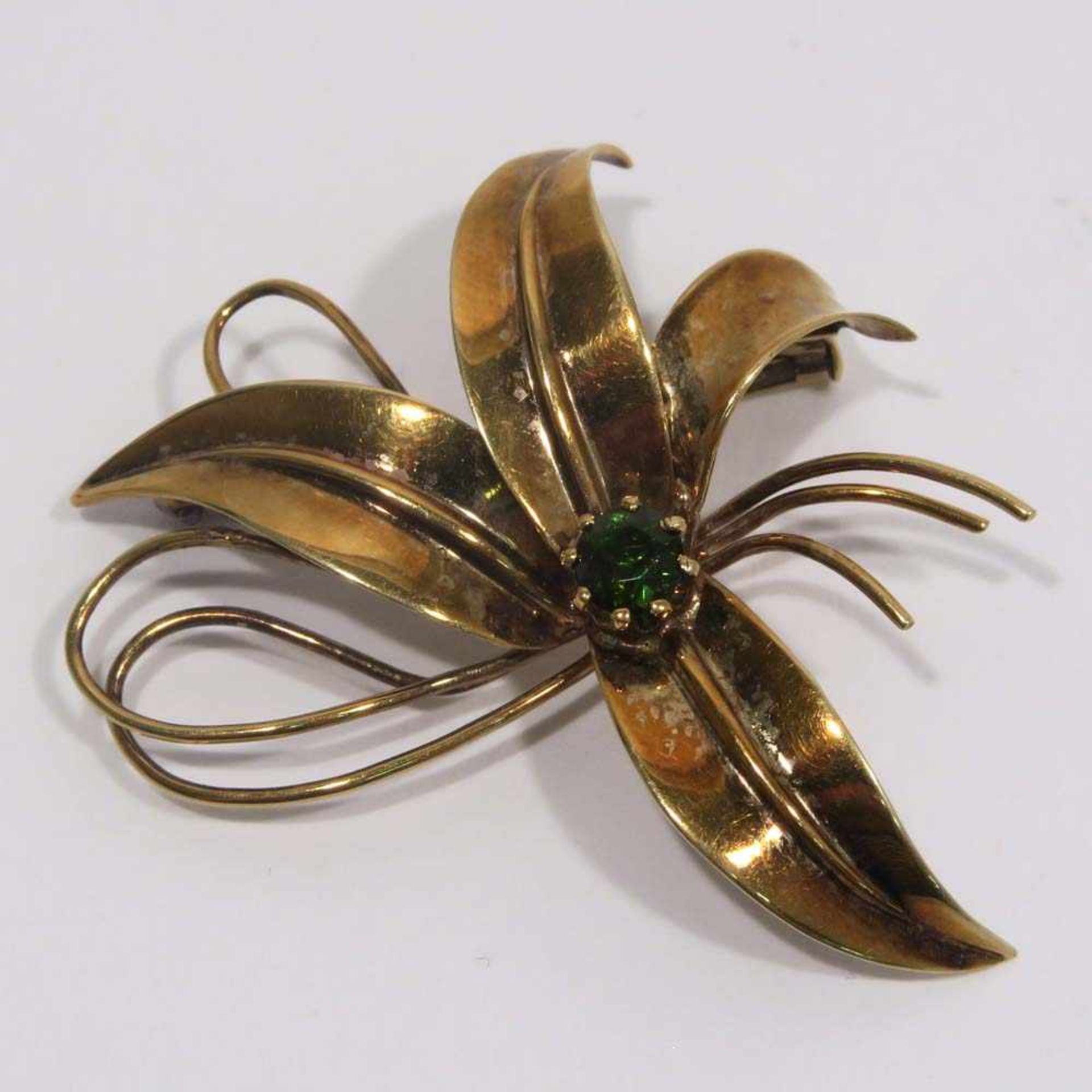 BroscheIn Form einer Blume. 14 K GG, Marke (585), mit einem grünen Stein. L. 4,3 cm. 5,4 g.