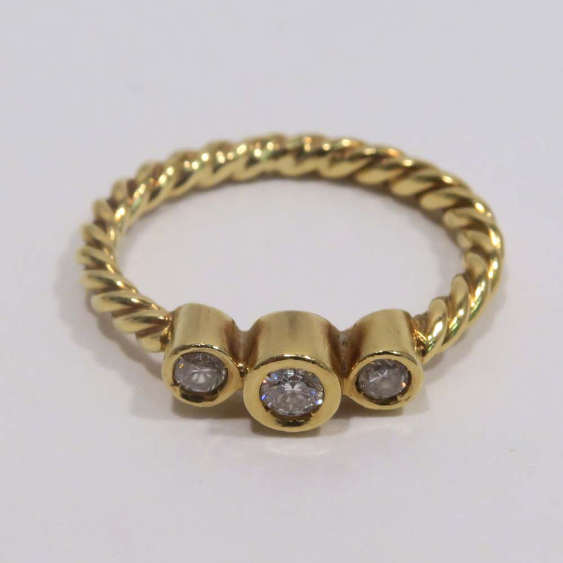 Ring18 K GG, Marke (750). Gedrehte Ringschiene, mit drei Brillanten, zus. ca. 0,2 ct., besetzt.