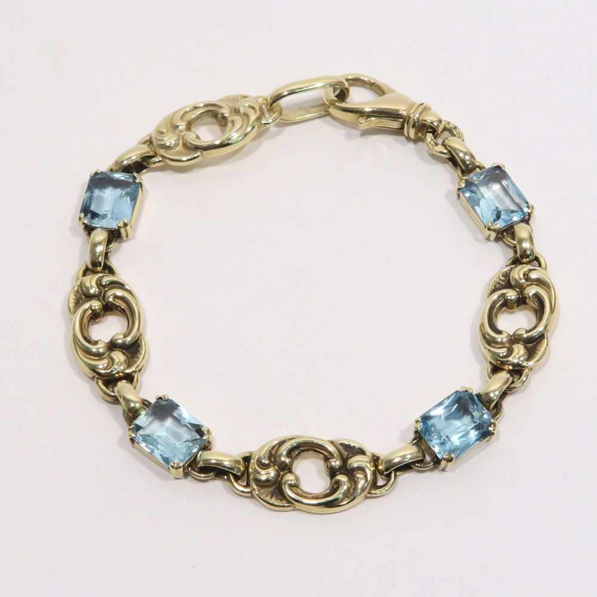 Armband14 K GG, Marke (585). Wohl vier Aquamarine im Wechsel mit Gliedern im Rocailledekor. L. 17,