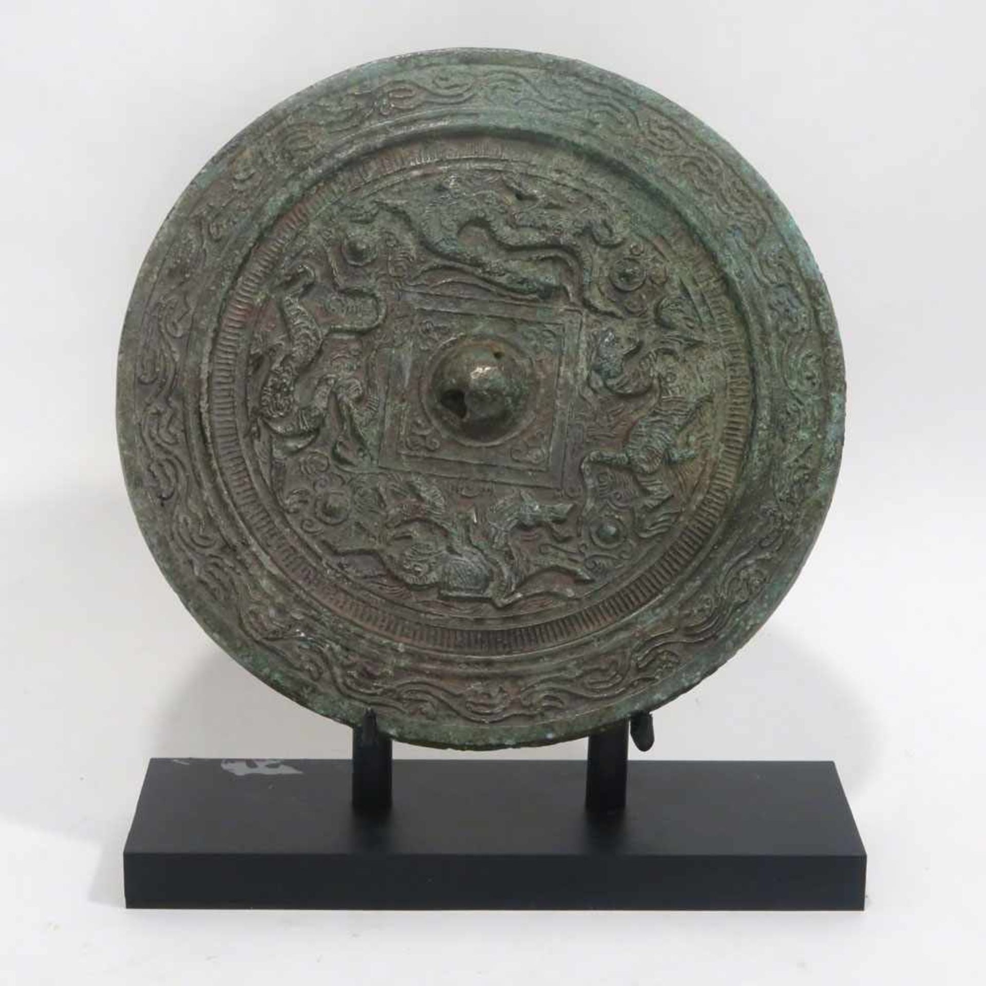 SpiegelChina, wohl im Han-Stil. Bronze, grün-braun patiniert. Rund, reliefierter Ornament- und