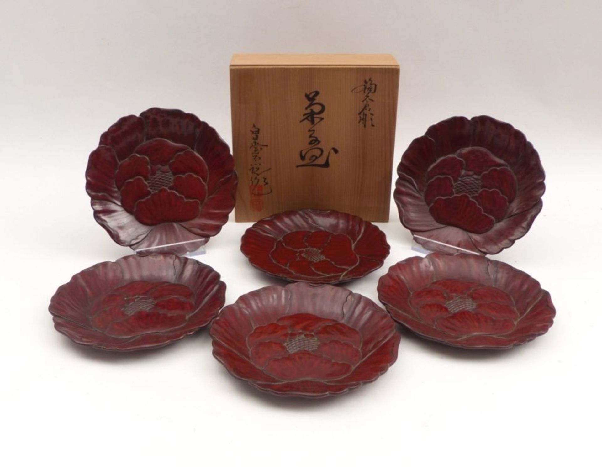Sechs kleine Teller in BlütenformJapan, 20. Jh.Holz, oberseitig im Relief beschnitzt und rotbraun