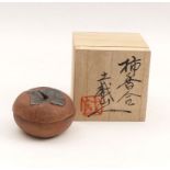 Box with cover in form of a persimmon fruitJapan, 20th C.Stoneware, partially dark glaze.H. 4,5