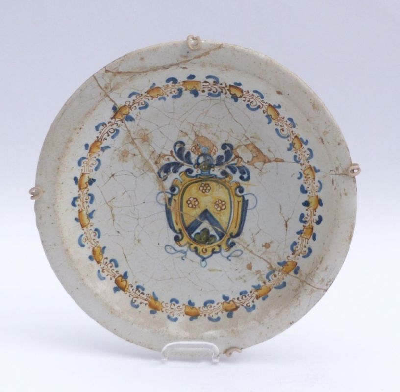 Plate with coat of armsItaly, 18th c.Centre with coat of arms in leaf wreath frame. Majolica painted