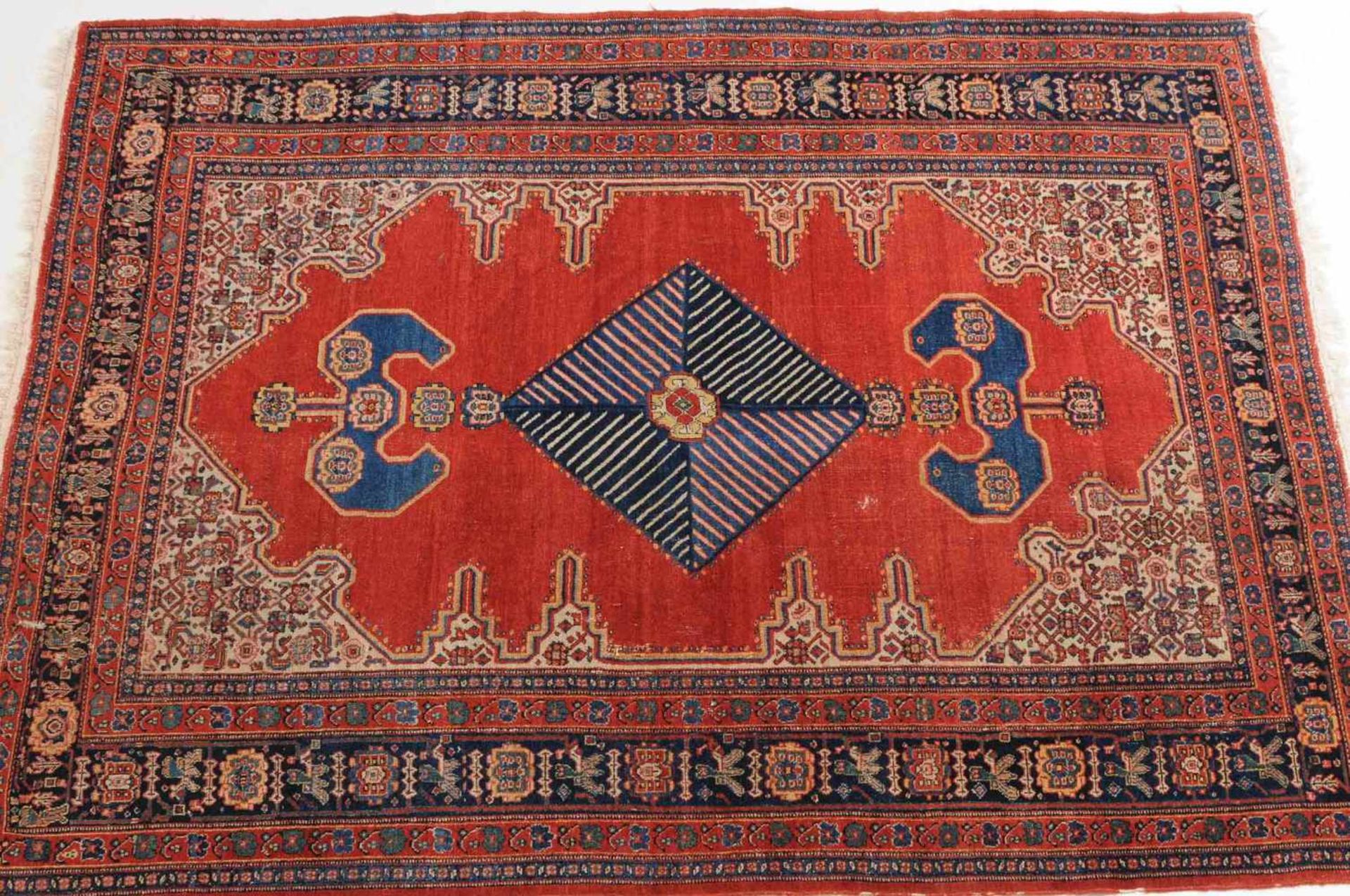 SenneW-Persien, um 1910. Im ruhigen ziegelroten Feld figuriert eine elegant angelegte blaue - Bild 2 aus 11