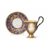 KPM BerlinUm 1820. Tasse mit Untertasse. Porzellan, matter blauer Fond mit goldenen Ranken, auf