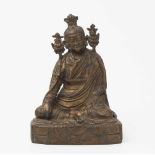 Figur eines GurusTibet/Nepal. Bronze mit Resten einer Vergoldung. Auf einem Kissen in lockerer