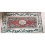 A small green and rust ground Rug. 135 x 75cm.