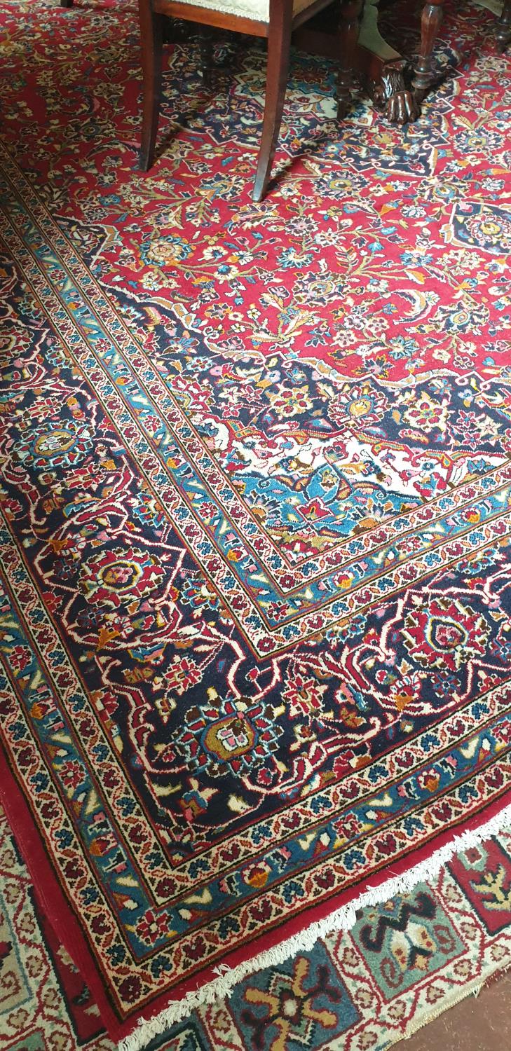 A fine woven Iranian carpet with red ground of Kashan origin traditional design. L404cm X W303cm.