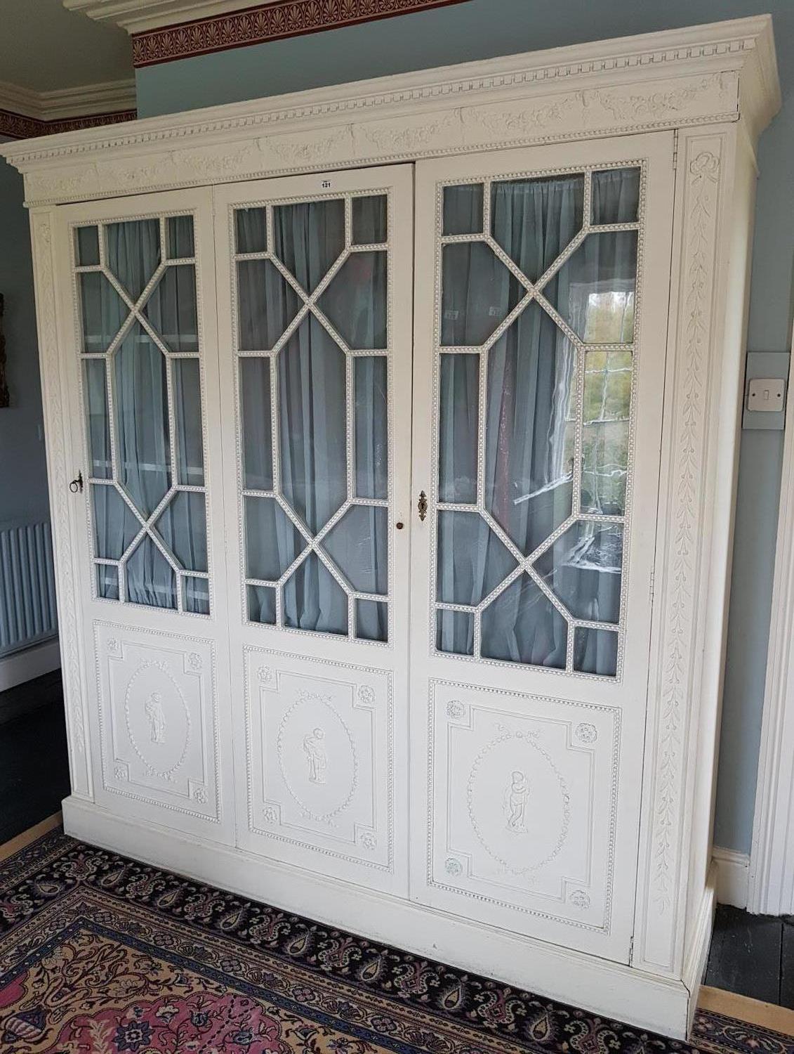 A three door Painted Wardrobe with a swagged top cornice and glazed doors on top of a classical