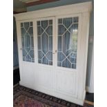 A three door Painted Wardrobe with a swagged top cornice and glazed doors on top of a classical
