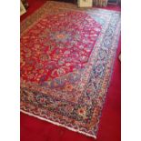 A deep Red Ground hand woven Persian Mashad Carpet. 283 cms x 193 cms.