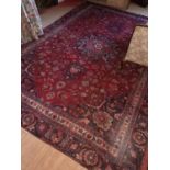 A red ground Persian Mashad Carpet with a unique medallion design. 310 x 223cm.