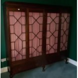 An Edwardian Mahogany four door Gentlemans Wardrobe with glazed astragal doors and pleated fabric.