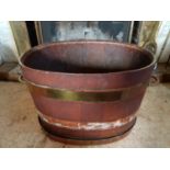 An Irish Georgian Mahogany oval Peat Bucket with brass strapping and lifting handles.