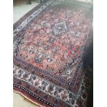 A washed red ground Persian Ceroc Rug with traditional medallion design. 310 x 210cm.