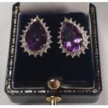 A pair of gold and diamond tear drop earrings with a large amethyst centre.