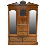 A Victorian oak wardrobe, the central carved cupboard door over three drawers, flanked by mirrored