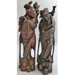 A pair of Japanese carved hardwood figures, inset with silver decoration, depicting a man and a