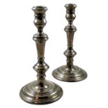 A pair of silver candlesticks, London 1975, the cotton reel scones to a baluster stem with a