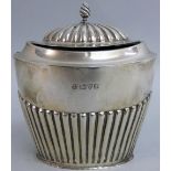 A silver tea caddy, by Barker Bros, Chester 1911, of oval half fluted form with a flame finial,