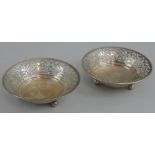 A pair of silver pin dishes, Birmingham 1919, of circular pierced form, raised on three ball feet,