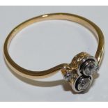 An Edwardian gold and two stone diamond twist ring, milligrain collet set with old cut stones,