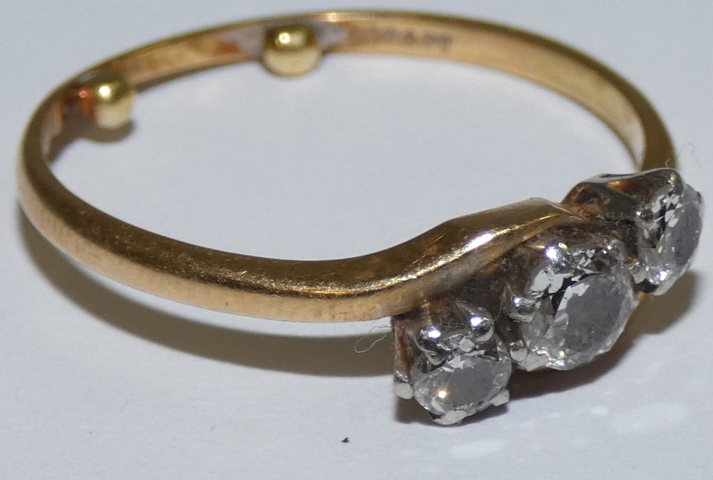 An 18ct gold three stone diamond ring, claw set with an old cut stone, flanked by smaller stones,