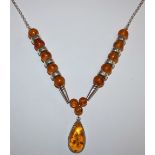 A silver and amber bead necklace with tear shape drop