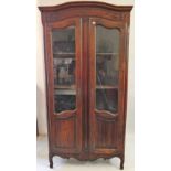 An early 20th century oak bookcase, the shaped part glazed doors with carved mouldings, raised on
