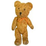 A vintage straw filled teddy bear, with gold coloured fur and orange bow, height 38cm.