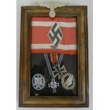 A framed selection of Nazi memorabilia, including Hitler Youth armband, Eagle Lapel badge, Iron