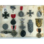 A mounted collection of fifteen WWII German medals and badges, to include Iron Cross, Drivers Badge,