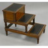 A set of mahogany library steps, composed of three leather topped treads, the top hinged for a
