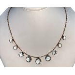 An Edwardian 9ct rose gold aquamarine necklace, the graduated milligrain collet set circular