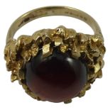 A 9ct gold and garnet dress ring, the cabochon stone set in an abstract block work mount, size M,